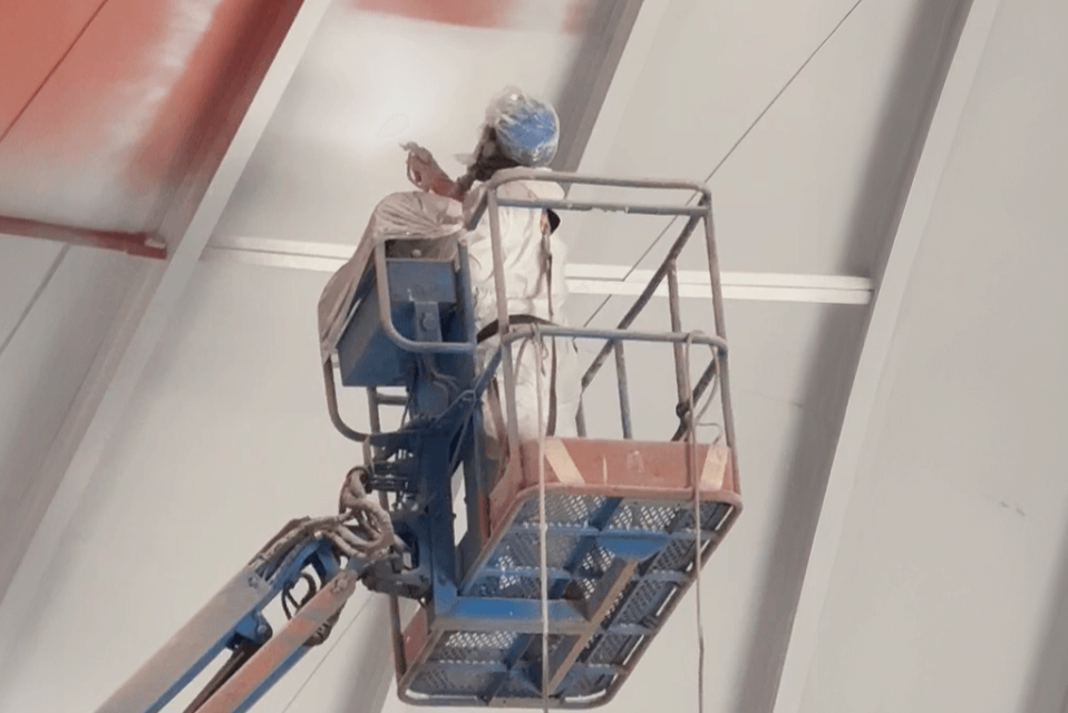 Worker using an airless spray system on elevated platform for industrial coating application